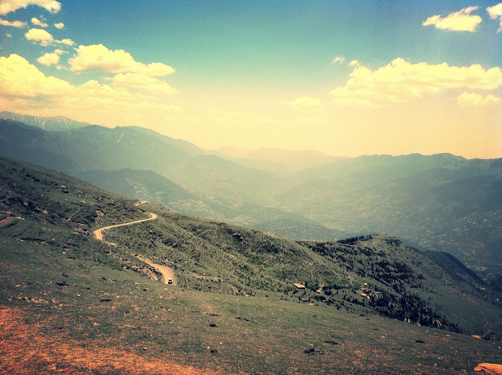 A winding mountain road disappearing into hazy Himalayan ridges